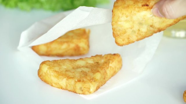 Close up of male and female hands take breaded potato hash brown from paper bag, on background of fresh salad and olive oil. Vegetarian Food Concept. Fast food
