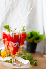 Crystal bakery with a drink, homemade cold juice with mint with fresh berries on a light background. Selective focus.
