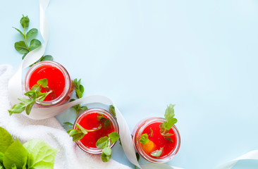 Glasses of homemade cold juice with mint with fresh berries on a light background. Selective focus.