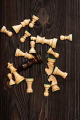 Top view of unique brown king among white chess pieces on wooden background