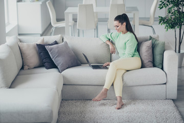 Obraz premium Portrait of her she nice attractive lovely smart clever intellectual cheerful focused girl sitting on divan using laptop supporting clients at light white interior room studio house living-room