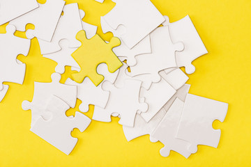 Top view of unique piece of puzzle among another on yellow