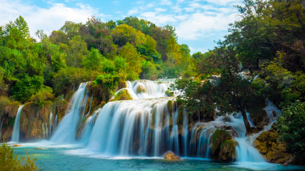 Fototapeta na wymiar A large waterfall among green trees and bushes