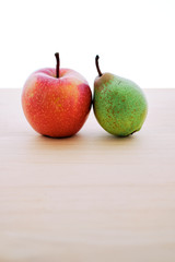 Appetizing red apple and pear on wooden table and white background