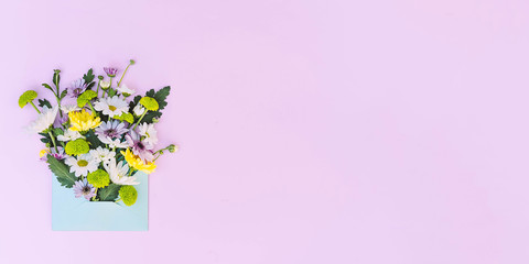 Flower arrangement in an envelope on a pink background.