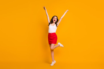 Full size photo of funny crazy cheerful lady raise hands crazy weekend sunny weather summer day wear casual white tank-top red mini skirt shoes isolated yellow bright color background