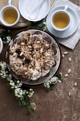 Chocolate cake with peanuts on table with tea and flowers