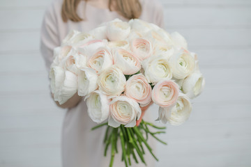 White peony roses bouquet in girl's hands by the Brick wall