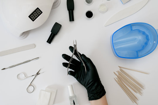 Tools for manicure hand in black glove - Powered by Adobe