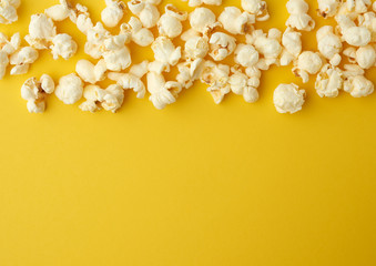 white delicious popcorn on a yellow background, place for an inscription - obrazy, fototapety, plakaty