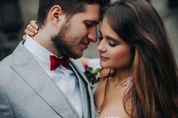Beautiful bride and groom embracing and kissing on their wedding day outdoors