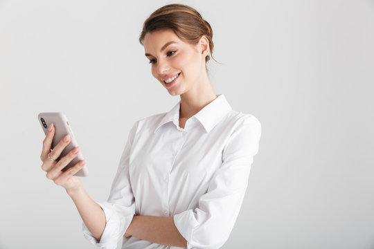 Image of pleased beautiful woman smiling and typing on mobile phone