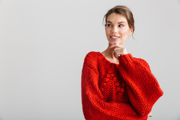 Image of joyful pretty woman in red sweater smiling and looking aside