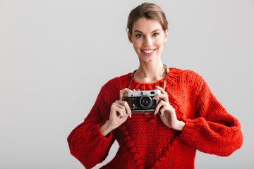 Image of young cheerful woman smiling and using retro camera