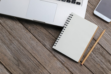 Blank notebook with laptop beside on wooden table