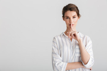 Image of serious nice woman showing silence gesture on camera
