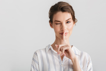 Image of pleased nice woman showing silence gesture and winking