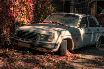 Old rusty russian car. Abandoned Soviet dirty car covered with leaves.