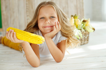 Child with corn. Child girl with corn in the studio. Child with vegetables.