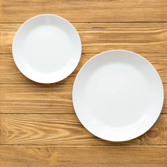 Empty white plates on a brown wooden table, square snapshot