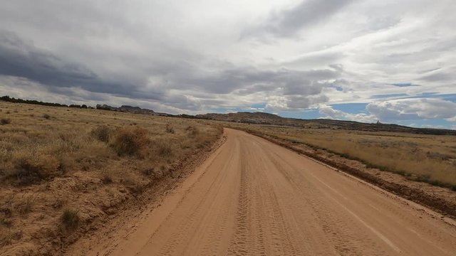 Desert landscape dirt road valley POV. San Rafael Swell geologic landscape south Utah. Sandstone limestone sedimentary valleys, canyons, gorges. Hikers,  off road all terrain vehicle (ATV) recreation.