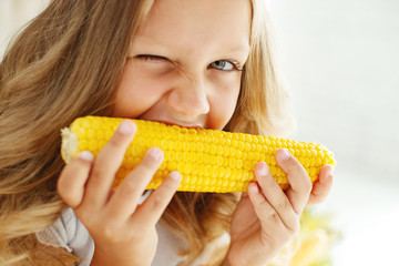 Child with corn. Child girl with corn in the studio. Child with vegetables.