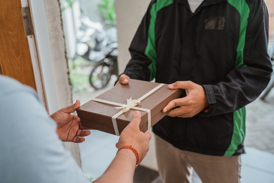 uber driver courier delivering gift box to a man in his house
