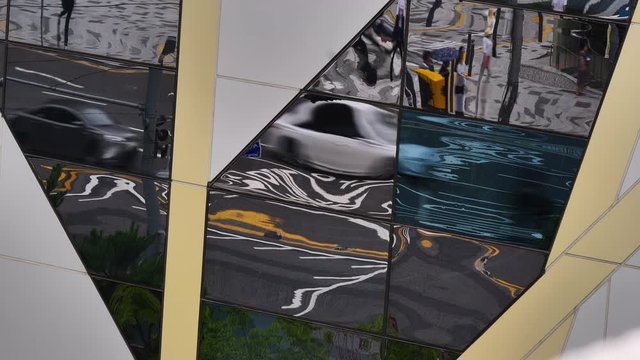 Reflections of high speed pedestrian and automobile traffic on glass building front 