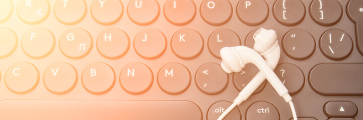 Podcast record. headphone at computer keyboard. Audiobook and podcasting. Audio technology. Home school teaching. Edit episode. Flatlay earpods. Horizontla banner