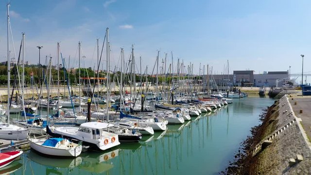 Aerial, rising, drone shot over boats at the Doca de Belem dock, revealing buildings on the coast of Lisbon, sunny day, in Lisboa, Portugal