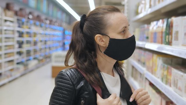 A woman in a protective antiviral mask in a supermarket selects products on the shelves. An empty store during the quarantine period due to the pandemic.