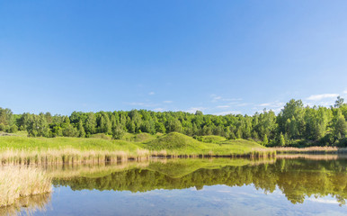 Fototapeta na wymiar Green hills with reflection in the lake water