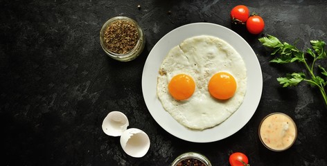 Fototapeta na wymiar Fried eggs in a white plate. Beautiful fried eggs. Tasty breakfast. Top view, dark concrete background. Free space for text