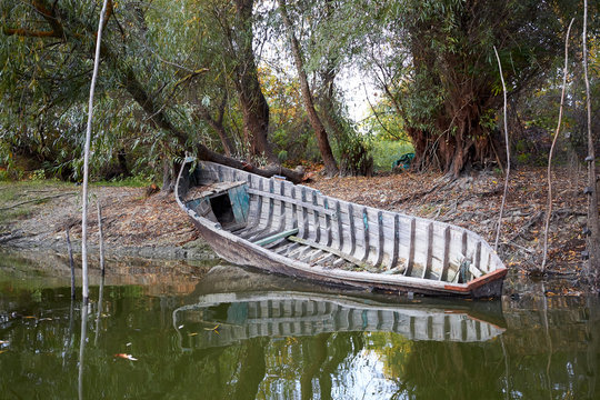 Old broken wooden fishing boat on the river shore at autumn