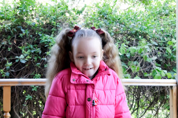 a little girl in a pink jacket is very surprised and delighted with something looks at the bottom