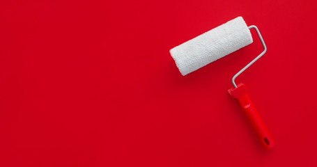 The concept of construction malar works. New clean white paint roller on a red background. Copy space