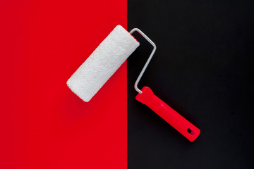 The concept of construction painting work. New clean paint roller on black and red background