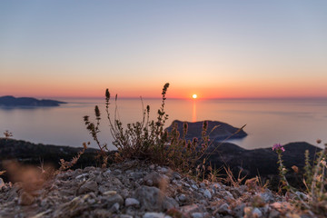 sunset at sea seen from a viewpoint in Kefalonia, Greek island, the water is calm and the sky takes...