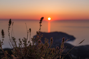 sunset at sea seen from a viewpoint in Kefalonia, Greek island, the water is calm and the sky takes on orange tones