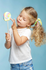 A child with a candy. Little girl with a round candy in the studio on a blue background.