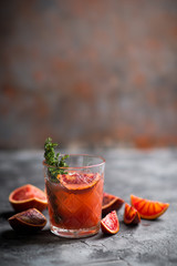 Old-fashioned cocktail with blood oranges and thyme on the rustic background. Selective focus. Shallow depth of field.
