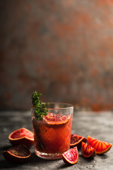 Old-fashioned cocktail with blood oranges and thyme on the rustic background. Selective focus. Shallow depth of field.