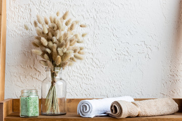 wooden shelf with blooming catkins, towel rolls and green sea salt in jar