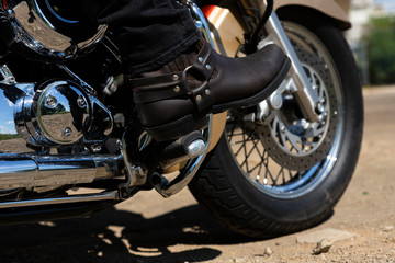 Biker riding a motorcycle. Bottom view of the legs in leather cowboy boots