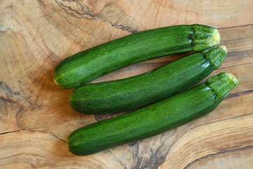 Green zucchini freshly picked on olive wood table. background.