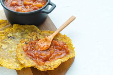 Fried banana with fried tomato on a white background. Typical dish of Colombian cuisine. Copy...