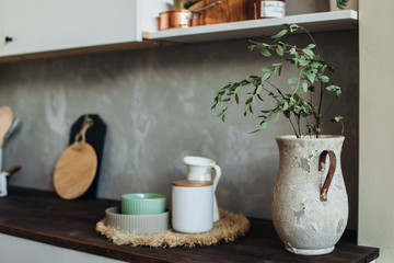 Kitchen appliances on a wooden table top, against a gray textured wall. Dry spikelets.vase in the foreground
