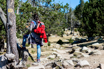 Rear view of a backpacker woman standing in a forest trail while looking away