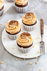 Chocolate dough cupcakes with peanut butter cream cheese frosting and chocolate bites. Rustic background