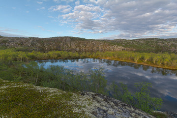 The reservoir is surrounded by hills and forest.Clouds are reflected in the water.Summer landscape.